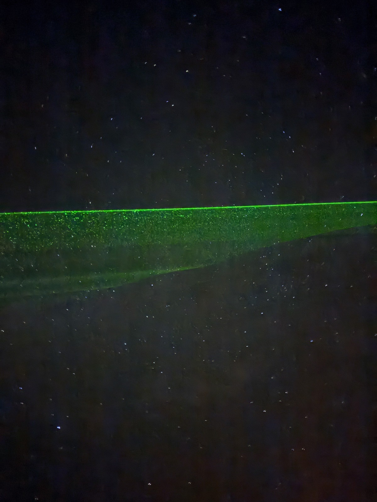 Green laser beam crossing the starry night sky above the dark horizon on Mount Teide