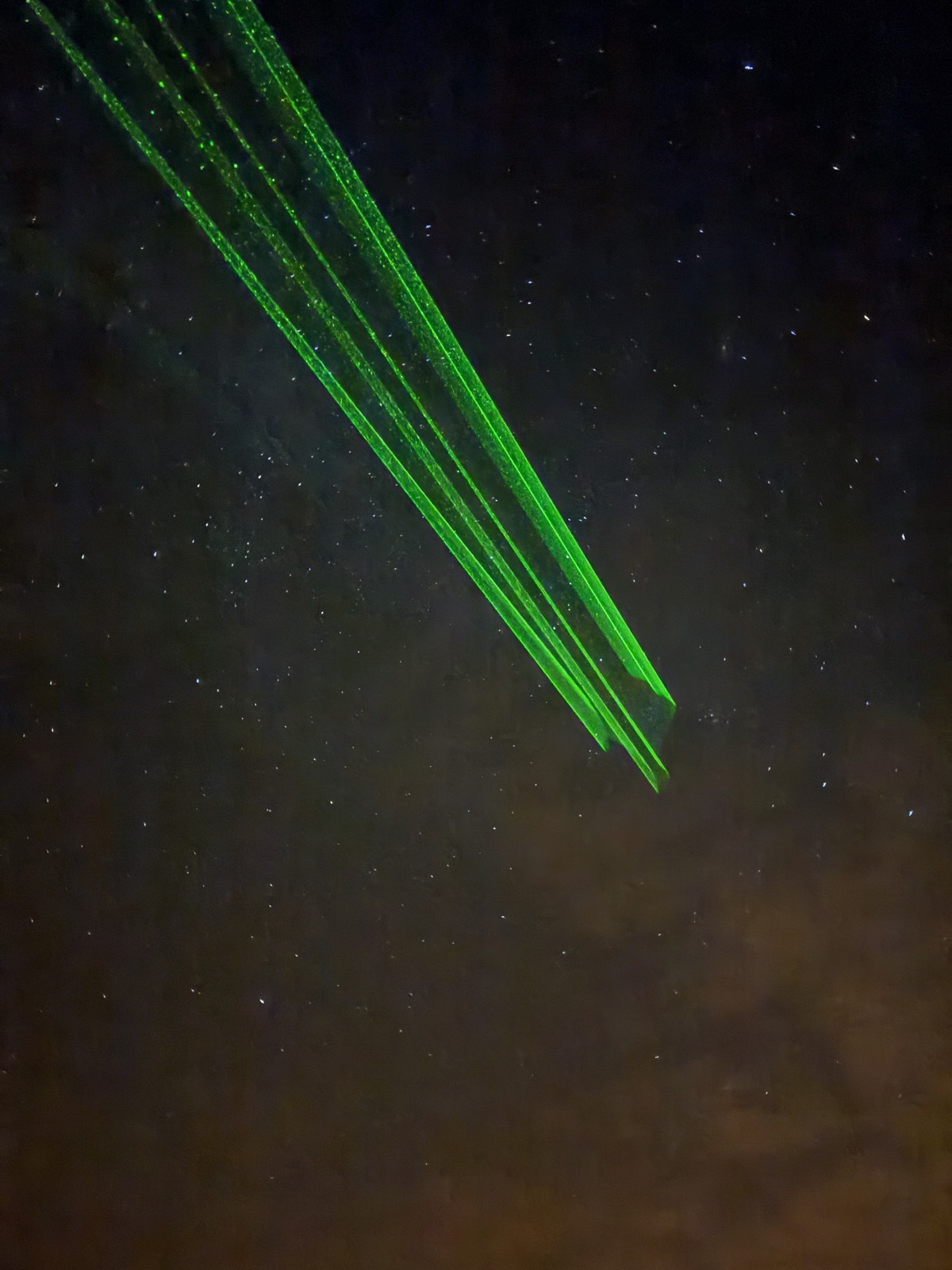 Green laser beams tracing constellations across a star-filled sky over Teide National Park